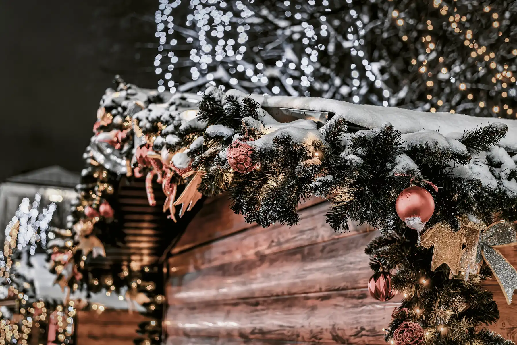 Casetta di legno innevata con ghirlanda, palline rosse e luminarie - mercatini di Natale di Greccio