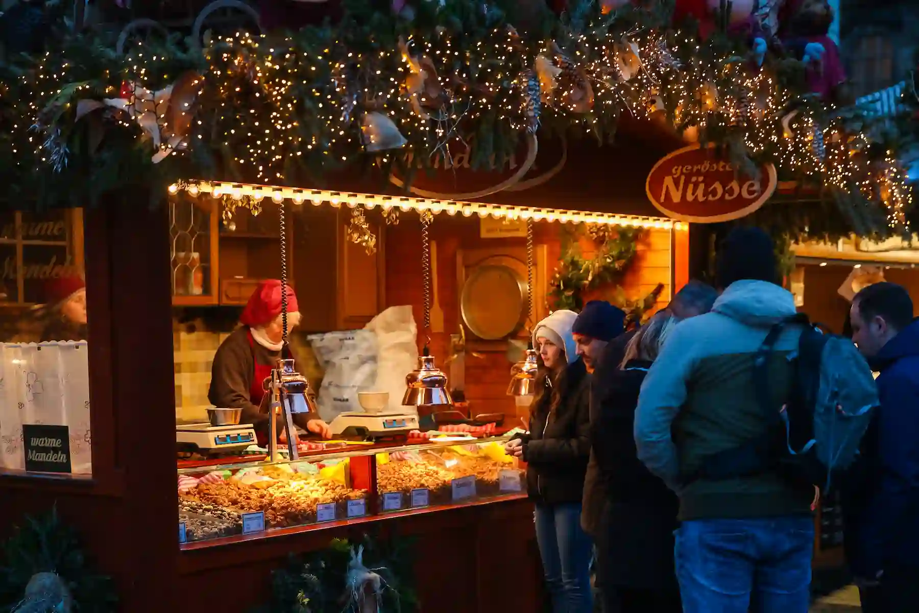 Bancarella di frutta secca e noci con visitatori davanti al banco - mercatini di Natale di Pordenone