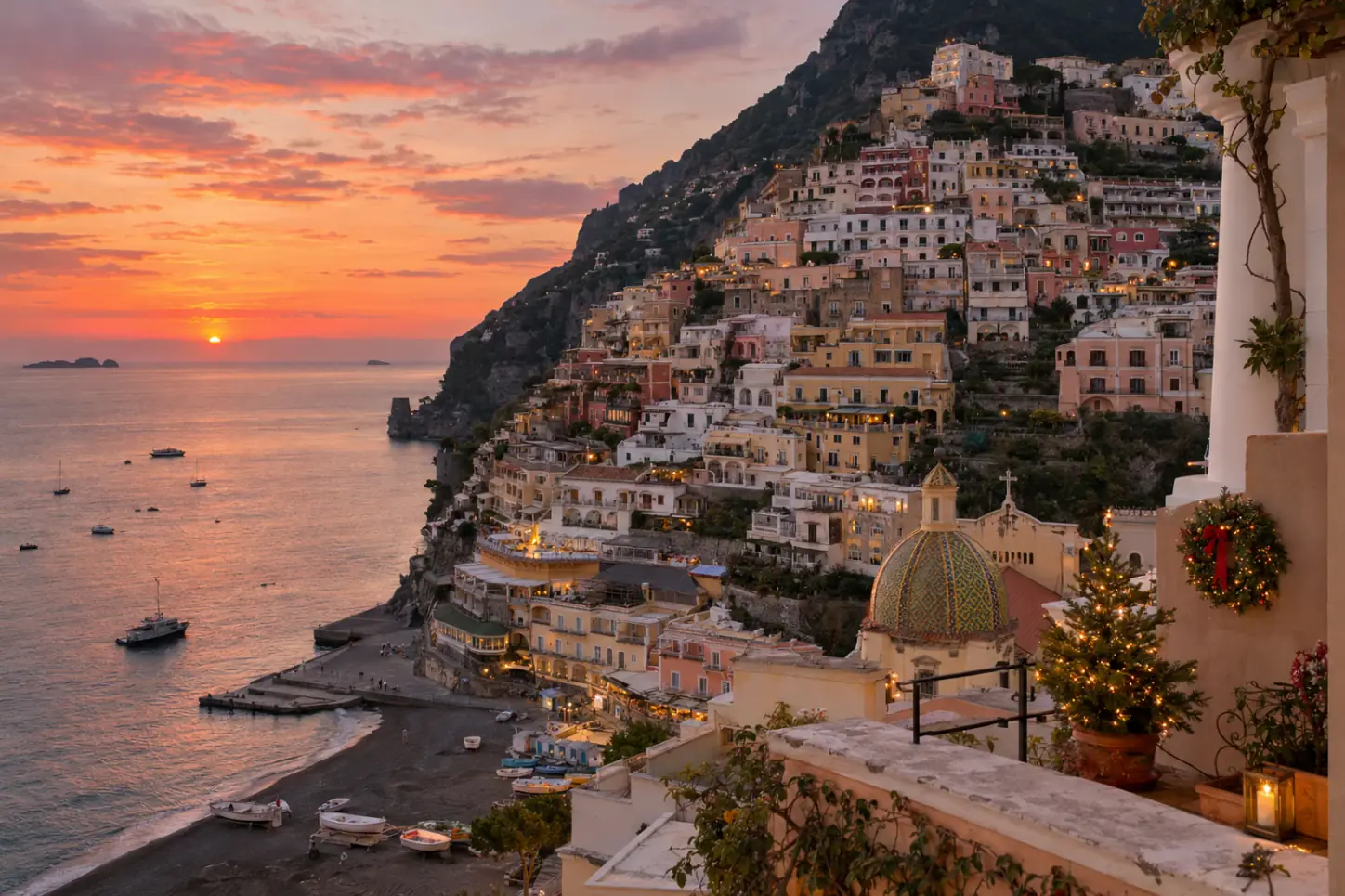 Positano sulla Costiera Amalfitana al tramonto in inverno, con le case colorate a cascata sul mare e le luci natalizie accese