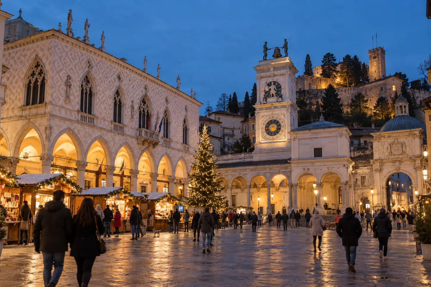 Piazza della Libertà a Udine di sera con la Loggia del Lionello, la Torre dell'Orologio, le casette di Natale e l'albero illuminato